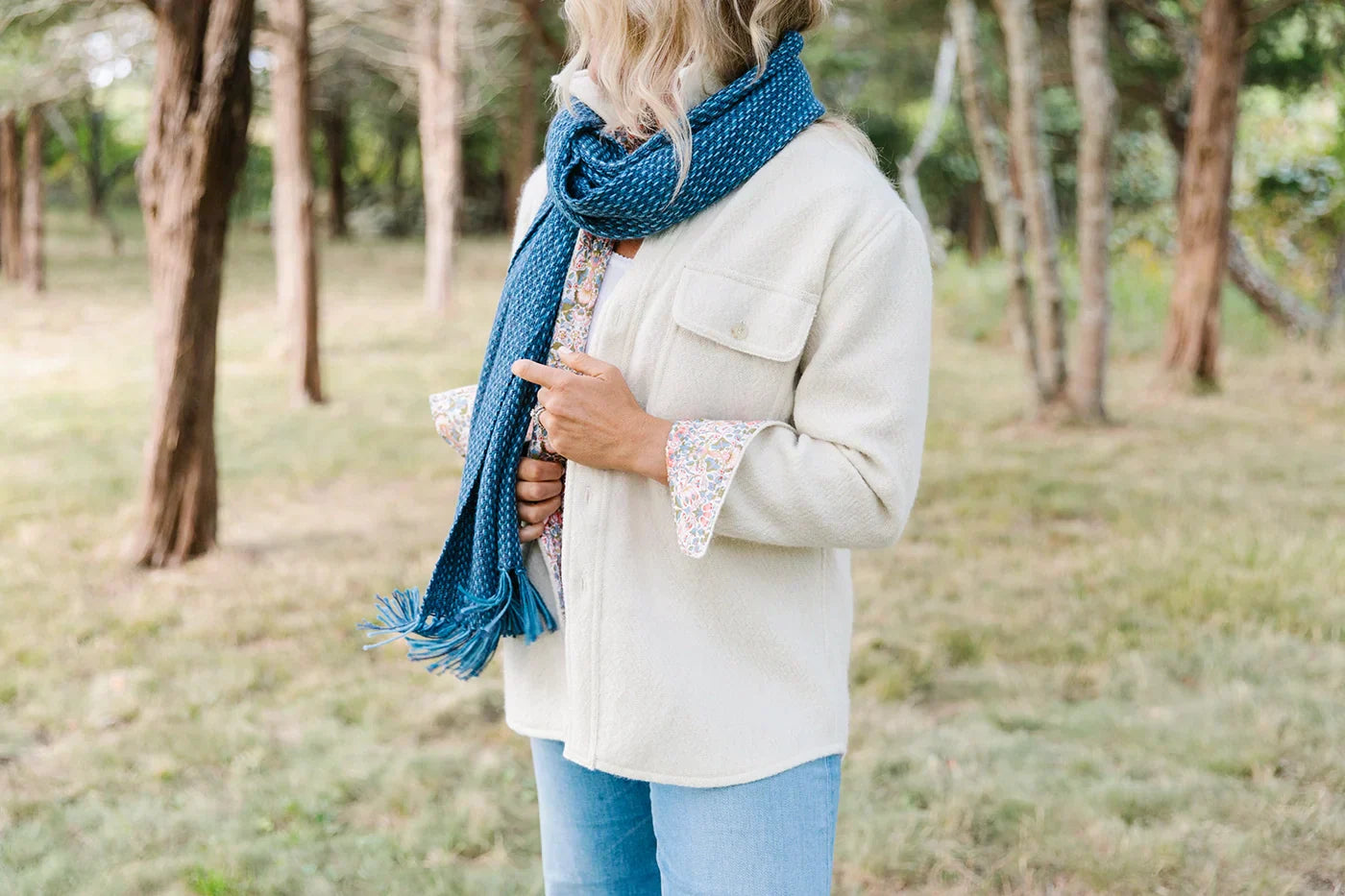 A woman standing outside wearing a white CPO jacket and a blue woven scarf