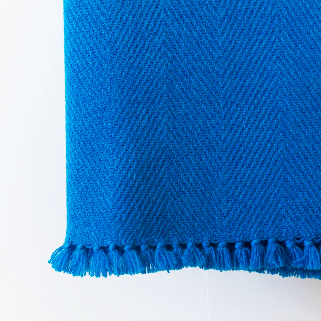 Close-up of a Nantucket Looms Hummingbird Blue cashmere throw, showing the luxurious soft weave and fringe detail on a white background.