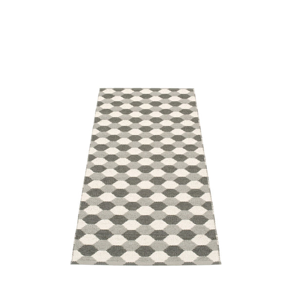 Long Pappelina rug featuring a monochrome geometric honeycomb pattern in shades of grey and white, set against a neutral backdrop.