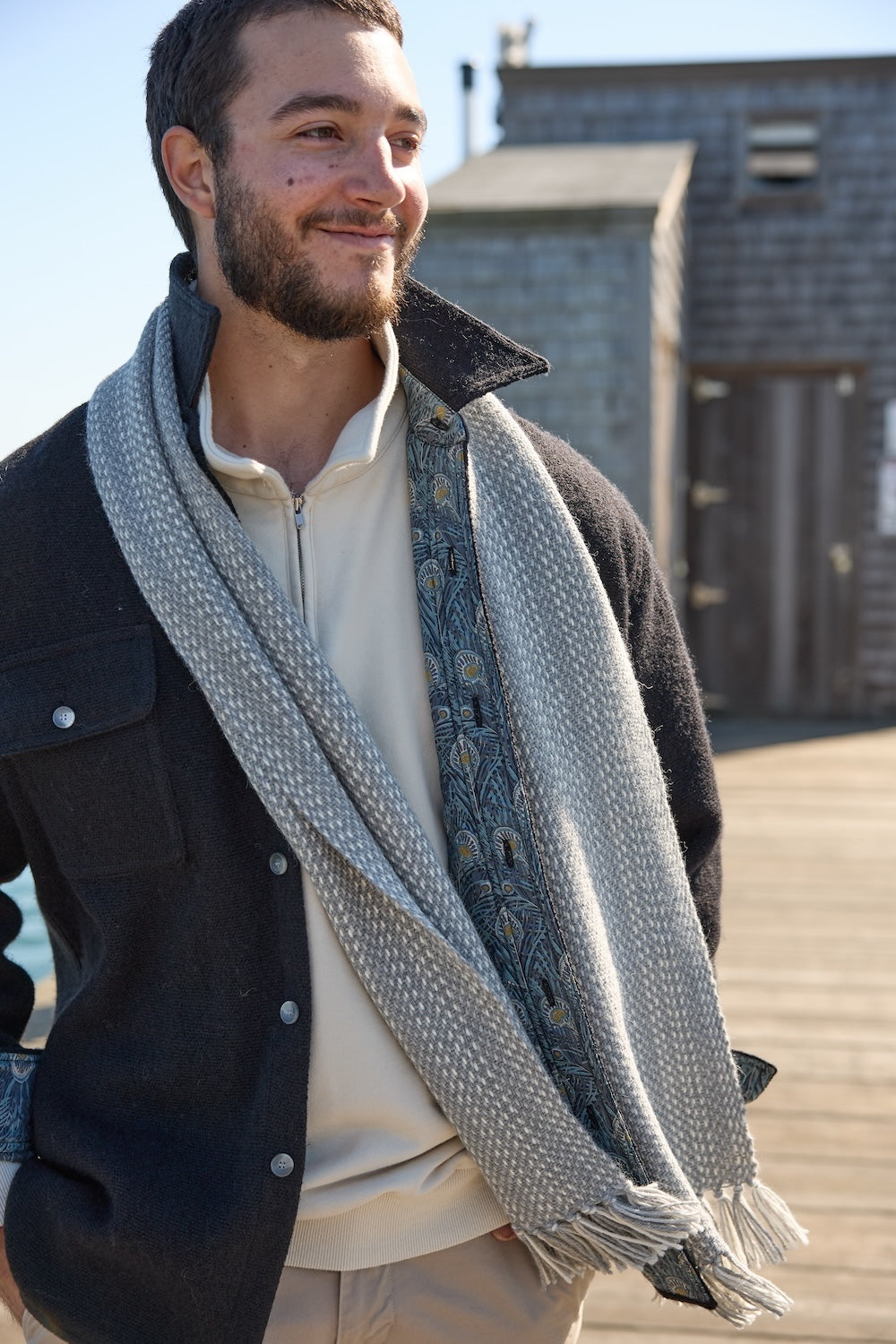 Man wearing a dark grey Nantucket Looms CPO jacket and light-colored scarf outdoors