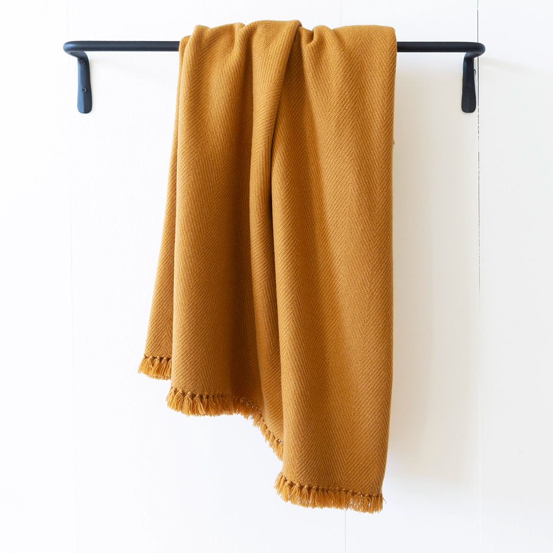 Nantucket Looms Chai Cashmere Throw blanket draped over a black metal rack.