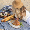 Person sitting on a beach with a picnic spread, including bread and cheese.