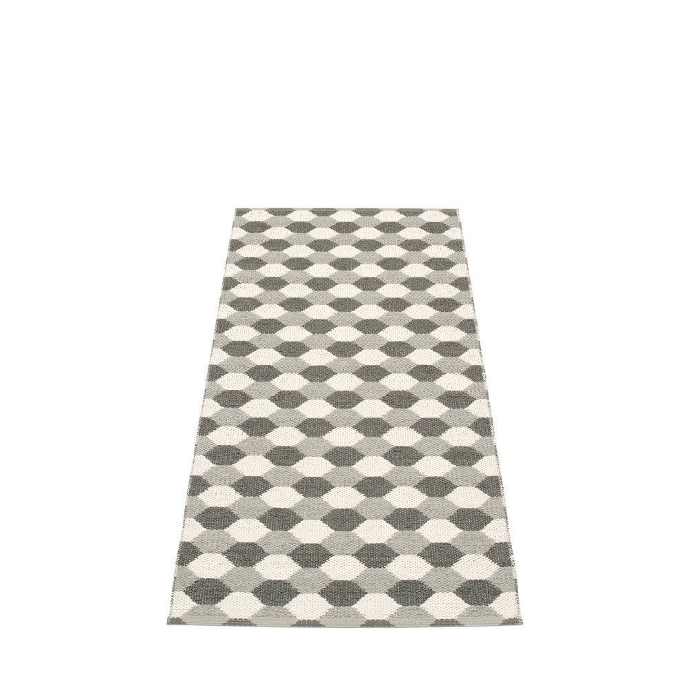 Long Pappelina rug featuring a monochrome geometric honeycomb pattern in shades of grey and white, set against a neutral backdrop.