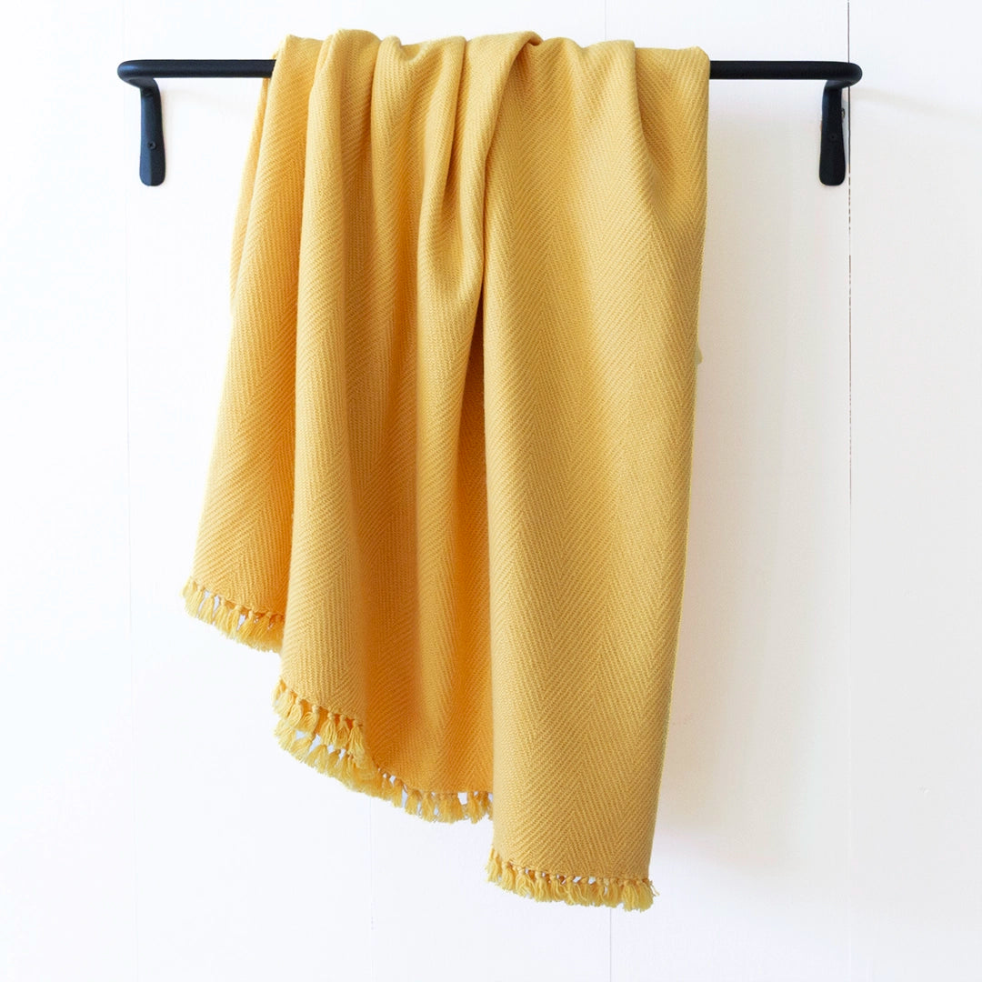 Nantucket Looms Sunflower Yellow cashmere throw blanket draped over a black metal rack.