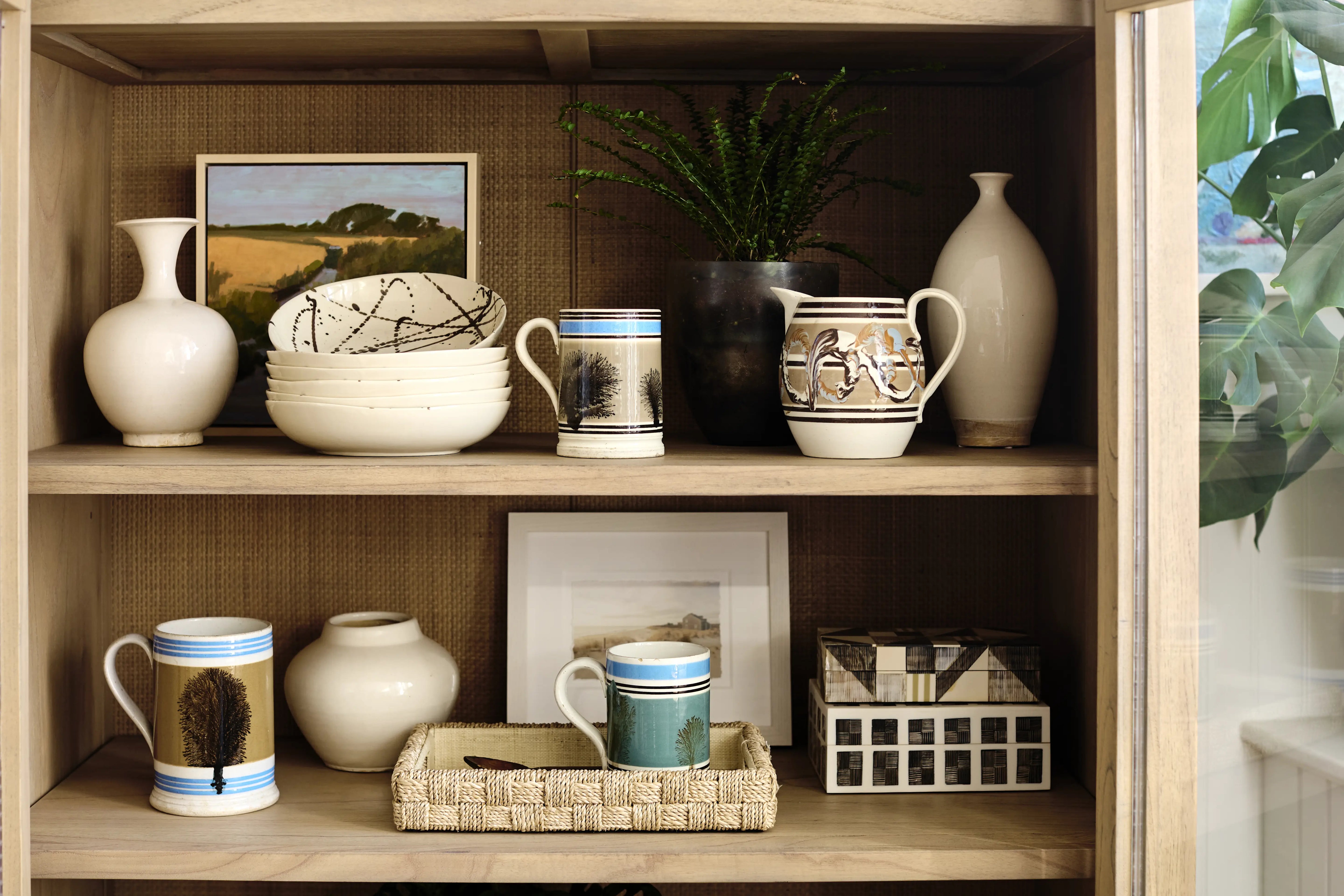 Decorative shelf with various ceramic items and framed pictures