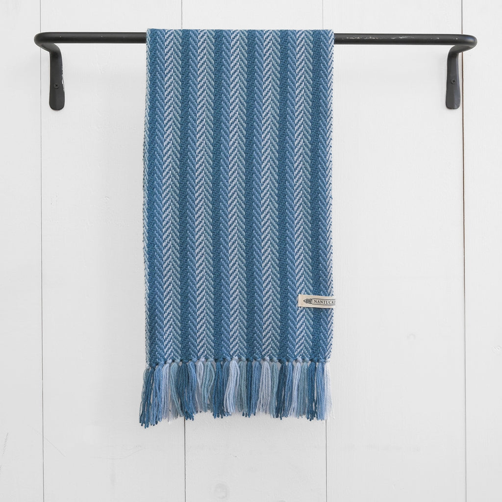 Nantucket Looms' handwoven alpaca throw in a deep herringbone pattern, with a visible brand label and tasseled edges, against a clean backdrop.